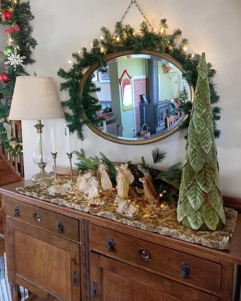 Bring a sense of style to your nativity scene and dedicate a sideboard or console table to showcasing these decorations. An antique wooden sideboard is the chosen display in this room, providing ample space for the scene. An oval mirror hangs on the wall, with twinkle lights highlighting the area...   Image: touchofthesouthdownunder Sideboard Christmas Decor, Nativity Scene Decor Ideas, Natural Wood Console Table, Nativity Scene Display, Best Mirror, Neutral Holiday Decor, Classic Wreath, Freestanding Mirrors, Pine Garland