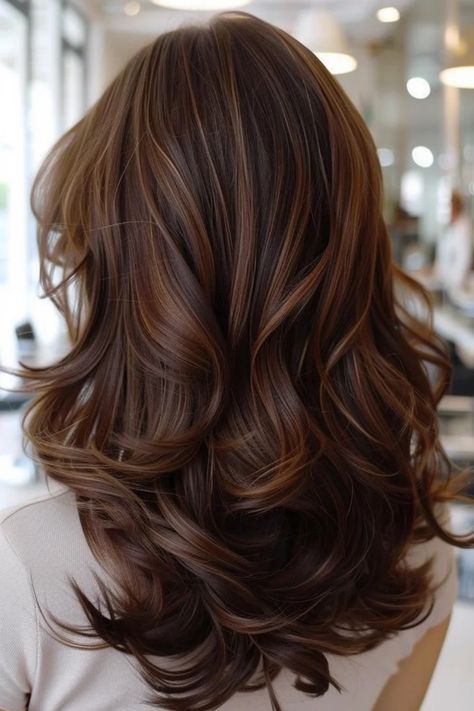 Wavy brunette hair with caramel highlights cascading down the back.