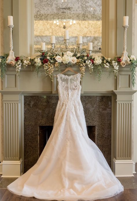 Wedding dress hanging on fireplace mantel Wedding Flowers Over Fireplace, Christmas Wedding Mantle Decor, Fireplace Mantle Flowers Wedding, Wedding Mantle Decorations, Fireplace Wedding Flowers, Fireplace Mantle Wedding Decor, Mantle Wedding Decor, Wedding Fireplace Mantle, Wedding Mantel Decor