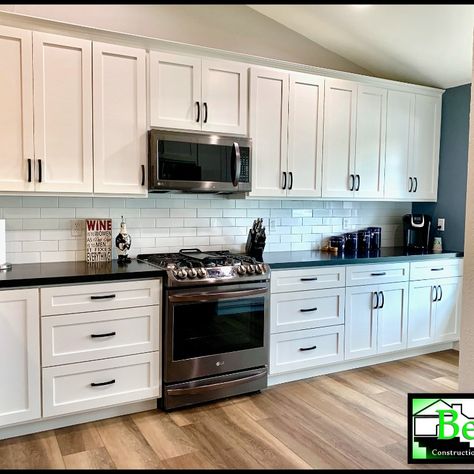 Here is the continuation of our progress post from 2/28. We wanted to share how custom cabinets look when first installed vs. after remodel completion. As you can see, a huge transformation happened. For this kitchen remodel we chose Shaker cabinets, vinyl plank flooring with warm tones, a white 3"x9” backsplash, gorgeous black stainless steel appliances, & a 33” Farmhouse sink. To finish the look, leathered Black Zimbabwe granite was used for the countertops, window sill & window bench. Stainless Steel Appliances Black Hardware, White Kitchen Cabinets With Black Stainless Steel Appliances, Light Gray Kitchen Cabinets With Black Stainless Steel Appliances Ideas, White Cabinets Black Appliances, Small Kitchen Redo, White Kitchen Cupboards, Black Stainless Steel Appliances, Black Stainless Appliances, Black Stainless Steel Kitchen