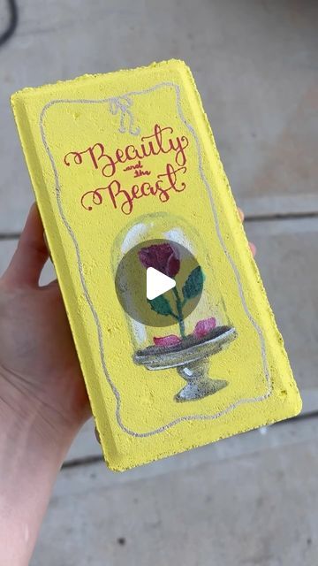 Melani Alberts on Instagram: "Should i add more brick paver books to my garden library? This time we had Beauty and the Beast. Bricks: @homedepot markers: @grabieofficial #brickpaverbook #brickpavers #beautyandthebeast #gardendiy" Painted Brick Books For Garden, Painting Bricks To Look Like Books, Garden Book Bricks, Book Bricks Garden, Bricks Painted Like Books, Book Pavers, Brick Books Garden, Brick Library, Paint Bricks