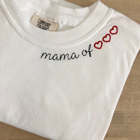 "My absolute favorite tee! This custom tee can be customized to your preferred thread color and is stitched on a Comfort Colors short sleeve unisex tee. \"Mama of\" will be stitched along the collar along with the number of hearts to represent each child! For shirts that require more hearts, they may need to be stitched on multiple lines.  Please wash on gentle cycle and dry on low.  If you are wanting a different design, wording, or a different clothing style, please send me a message so we can discuss the details. Please include thread color at checkout If you need this order rushed, please add these to your cart: https://www.etsy.com/listing/1043569716/rush-my-order-for-t-shirts?ref=shop_home_active_19&frs=1 Rush my order + Priority shipping, click here: https://www.etsy.com/listing/104 Embroidery On Tshirt, Embroidery Tshirt Ideas, Collar Embroidery Design, Neckline Embroidery Designs, Embroidery Sleeves, Embroidery Shirts, Collar Embroidery, Projets Cricut, Embroidery Shirt