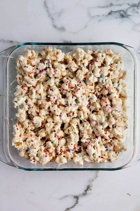 top down view of funfetti marshmallow popcorn treats in glass baking dish Mallow Magic Popcorn Recipe, Cake Batter Popcorn Recipe, Marshmallow Pretzel Treats, Marshmellow Popcorn Easy, White Chocolate Puffcorn, Popcorn Marshmallow Treats, Funfetti Popcorn Recipes, Marshmallow Christmas Treats, Easter Rice Crispy Treats