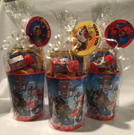 Paw Patrol Party Favors  • hard plastic cups  ($.69@Christmas Tree Shops)  • Crayola crayons (Amazon for about $.70/ea.) • Paw Patrol mini activity book (Party City for $.10/ea) • Mini play-doh (10 pack for $4.99 @ Christmas Tree Shops) • Mini Paw Patrol bubbles (Party City for $.15/ea)  All wrapped in cellophane with a little white curling ribbon with a "lollipop" tag printed from NickJr. for free   Great for ages 2-7 or so. Paw Patrol Party Cups, Paw Patrol Candy Table Ideas, Paw Patrol Party Centerpieces Diy, Paw Patrol Favors Ideas, Paw Patrol Favor Bags, Paw Patrol Party Bags Ideas, Paw Patrol Goodie Bags Ideas, Paw Patrol Party Table Ideas, Paw Patrol Birthday Favors