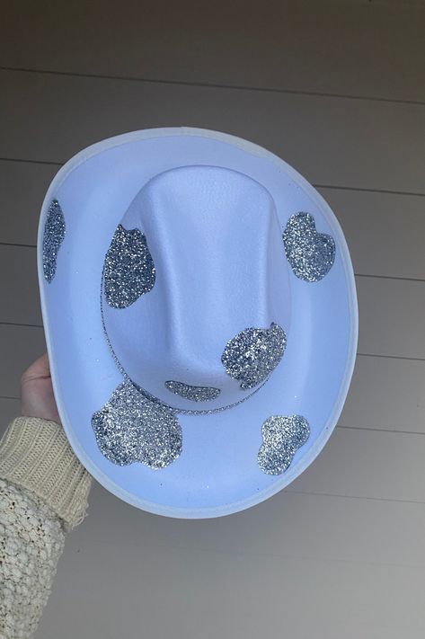 Silver Glitter Cowprint with Rhinestone Band Cowboy Hat. This cowboy hat is the perfect addition to your party, events, and even cute photos! This is an adult-sized, polyester cowboy hat sealed with silver cowprint glitter with a double rhinestone band. The glitter is only on the top of the hat ensuring that it will not get in your hair! The bottom of the hat is white. The hat circumference is 23 inches. Keep in mind that this is not a fitted cowboy hat, one size fits most but it ranges on the l Emerald Green Quinceanera Theme, Nfr Rodeo, Preppy Cowgirl, Outfit Vaquero, Cosmic Cowboy, Cow Birthday Parties, Custom Cowboy Hats, 17th Birthday Ideas