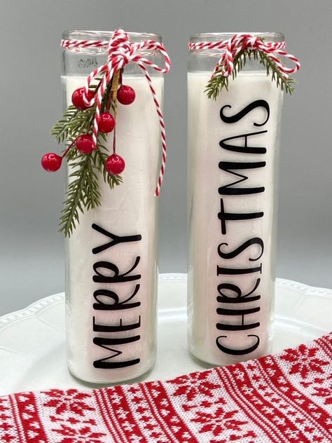 "This set of 2 glass pillar candles for Christmas features the words \"Merry\" and \"Christmas\". They are festively decorated with artificial greenery and holly berries tied on with red and white baker's twine. Ready to display on your holiday table, as a centerpiece, or in a tray display. The words are permanent vinyl. Each candle is 8\" tall by 2 1/8\" wide. Free shipping is included. This listing is for embellished candles only. Any other pictured items are to show display ideas." Red Christmas Centerpieces, Decorated Candles Ideas, Dollar Tree Christmas Candles, Fall Candle Crafts, Christmas Craft Show Ideas To Sell, New Christmas Crafts For 2023, Dollar Tree Crafts To Sell, Embellished Candles, Holiday Centerpieces For Tables