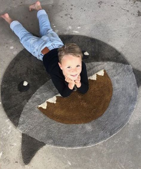 Large round grey shark carpet (with fins hanging out) for toddler boy or big boy bedroom decor. Little boy lays on carpet while smiling upwards at camera. Shark Room For Boys, Shark Nursery Theme, Shark Kids Room, Shark Bedroom, Shark Nursery, Shark Room, Nautical Nursery Boy, Shark Decor, Sharks For Kids