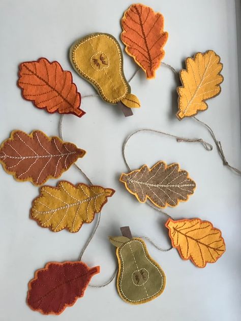 This gorgeous Autumn-inspired garland features eight wool-mix felt oak leaves and two felt pears.  They are strung on a jute twine which measures 1.20 metres in length and has loop holes at either end.  Each felt leaf measures approximately 12 cm in length and each pear measures approximately 13.5cm in length. The felt pieces can easily be removed from the twine and rearranged in whatever order you wish as they each have a sewn felt loop on the back. A beautiful garland for across a fireplace or doorway. Fall Wreath Felt, Holiday Garlands Diy, Stiff Felt Projects, Felt Autumn Garland, Thanksgiving Felt Garland, Felt Leaves Garland, Felt Fall Decor, Felt Pumpkin Pattern, Handmade Autumn Decorations