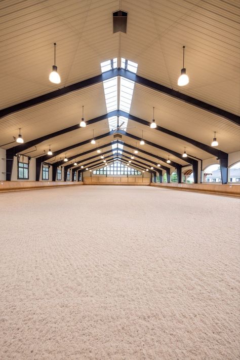 When creating this riding arena, we considered air flow, lighting, materials, the safety of horse and rider, and ease of access to the facility. With arched open-air windows on one side, and large fans overhead, air flow is never a problem. In fact, “garage doors” can be opened on the opposite length of the arena to make it a pavilion setting for maximum breeze. Large windows and skylights bring in plenty of light, while hand-bent wood bumpers keep horses safely away from the outside walls. Covered Riding Arena, Horse Riding Arena, Riding Arena, Barn Builders, Horse Arena, Dream Stables, Dream Horse Barns, Horse Facility, Indoor Arena