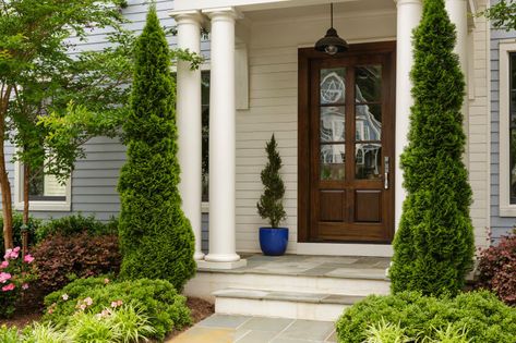 Posts of pine tree are free standing against the houses's white pillars. You can also see a spiral topiary planted in a blue pot. Front Door Styles, Small Front Yard Landscaping, Small Front Yard, Garden Wallpaper, Casa Exterior, Front Door Colors, Front Entrances, Outdoor Wall Lantern, Door Color