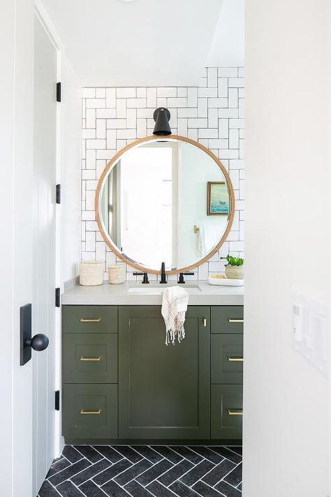 A round blond wood mirror hangs from a wall covered in white subway backsplash tiles arranged in a geometric pattern and contrasted with black grout. Olive Green Bathrooms, Powder Room Design Ideas, Green Bathroom Vanity, Green Vanity, Powder Room Decor, Herringbone Backsplash, Cottage Bathroom, Powder Room Design, Patterned Floor Tiles