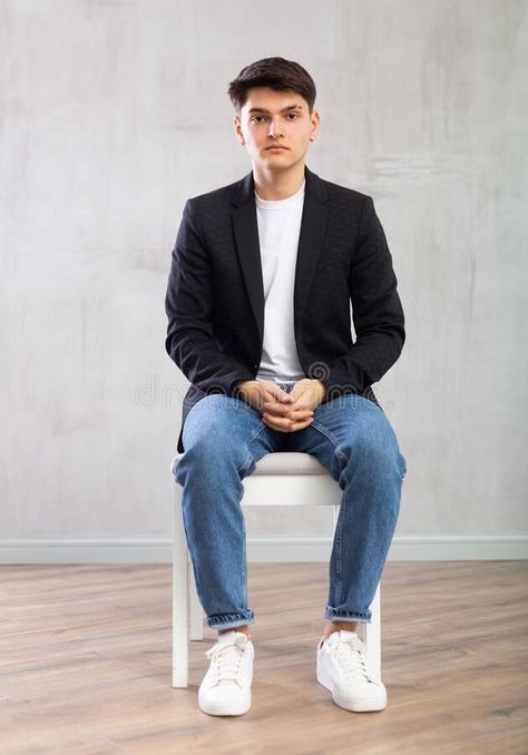 Charismatic young man sitting on chair in the middle of the room stock images Sitting Pose On Chair, Man Sitting In Chair Pose, Person Sitting Reference Chair, Men Sitting Poses, Sitting Pose Reference Chair, Man Sitting Pose, Sitting On Chair Poses, Person Sitting Reference, Man Sitting In Chair