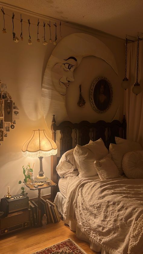 A cozy bedroom with an antique wooden bedframe topped with a vintage cream blanket and a cozy mix of pillows. Above the bed hangs a paper moon and dried flowers as well as old swag lights. To the left of the bed is a pretty vintage lamp on a small table filled with knickknacks and candles. Below, lent against the side are books and an old radio. Dreamy Room, Dream Room Inspiration, Apartment Inspiration, Cozy Room, Room Inspiration Bedroom, Room Ideas Bedroom, Aesthetic Bedroom, Dream Rooms, Dream House Decor