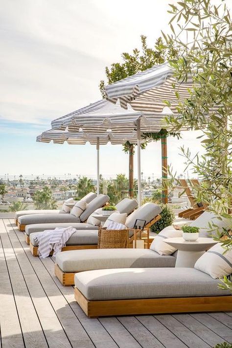 Gray striped outdoor umbrellas complement gray striped lumbar pillows placed on teak loungers with gray cushions. Outdoor Sunbed, Pool Umbrella, Pool Loungers, Brooke Wagner Design, Poolside Decor, High End Residential, Outdoor Cabana, Lounge Bed, Italy Villa