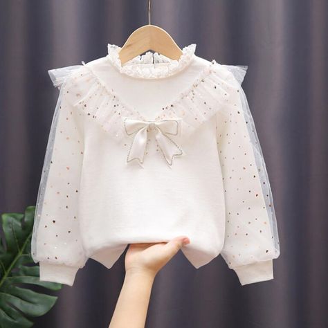 The White Bow Lace Long Sleeve Shirt is a beautiful and stylish pullover top designed for kids between the ages of 3 to 12 years. This shirt is perfect for the spring and autumn seasons, providing both comfort and elegance for toddler and teen girls. The shirt features delicate lace detailing and a charming bow accent, adding a touch of sophistication to the design. The long sleeves make it suitable for cooler weather, and the soft cotton fabric ensures a cozy and comfortable fit for all-day wea White Blouse With Bow, Lace Long Sleeve Shirt, Kids Activewear, Kids Blouse, Kids Dress Wear, Shirt Girl, Girls Blouse, Lace Long Sleeve, Children Clothes