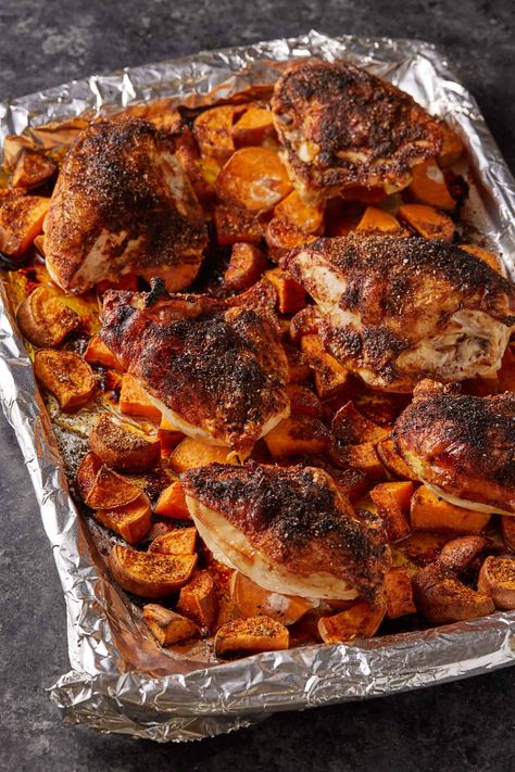 A rimmed baking sheet with roasted chicken and potatoes. Sheet Pan Chicken And Sweet Potatoes, Baked Chicken And Sweet Potatoes, Roasted Chicken And Sweet Potatoes, Chicken And Sweet Potatoes, Dinner With Chicken, Spicy Dinner, Easy Sheet Pan Dinner, Oven Roasted Chicken Breast, Roasted Chicken And Potatoes