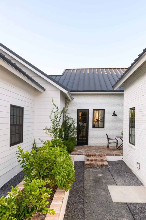 Step into this Arizona home with an elegant black and white palette White Exterior Brick, Classic Southern Home, Red Brick Pavers, Black And White Exterior, Black Metal Roof, Black And White Palette, White Exterior Houses, Brick Steps, Black Roof