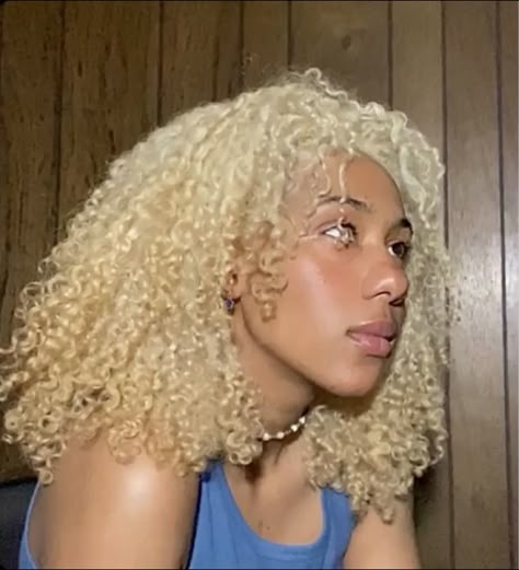 Brown skin girl with shoulder length, curly, blond hair, looking to the right. Blue tank top and beaded choker on. Infront of a dark wash wooden wall. Rosy cheeks and glowing skin. Platinum Blonde Hair Black Women Natural, Black Woman Blonde Curly Hair, Blonde Hair On Light Skin Women, 4b Blonde Hair, Blonde Hair Curly Natural Black Women, Platinum Natural Hair Black Women, White Blonde Hair Black Women, Platinum Blonde Curly Hair Black Women, Blonde Type 4 Natural Hair