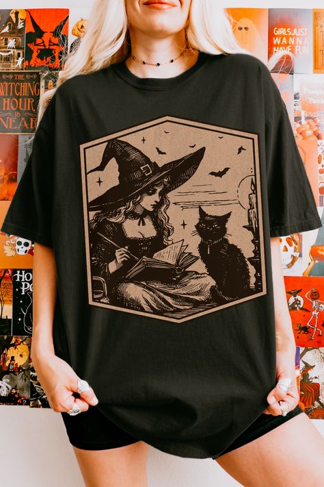 Featuring a graphic of a witch reading a book next to her loyal black cat, this tee is perfect for those who love witchy fashion and books. Ideal for Halloween or everyday wear, this vintage-style shirt gives spooky season vibes for book lovers. Embrace the witch aesthetic with this enchanting t-shirt! #WitchyFashion #BookLover #SpookyStyle #BlackCat #WitchAesthetic #HalloweenTee #MysticalVibes #VintageWitch #halloweenfashion #booklovergifts #falloutfits #salemwitchshirt #halloweenbats The Witch Aesthetic, Retro Halloween Witch, Black Cat Spooky, Witch Shirts, Book Club Shirt, Gothic Tees, Lovers Embrace, W.i.t.c.h Aesthetic, Vintage Witch