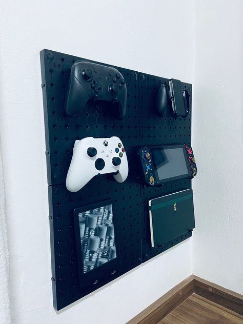 A picture of a pegboard holding some things like an xbox and nintendo controller and a sketchbook Pegboard Nintendo Switch, Video Game Corner Ideas, Gamer Pegboard, Fortnight Bedroom Ideas, Boys Game Bedroom, Pegboard Gaming Setup, Playstation Bedroom, Pegboard Gaming, Gamer Room Ideas Boy Bedrooms