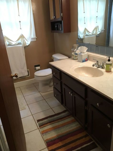 Does your builder grade bathroom need an update? Mine sure did...with a basic vanity and even more basic tile, my bathroom was in need of a face lift. I spent a weekend and less than $200 in paint and supplies to get a bright and airy guest bathroom.    Here is the "Before" shot. I had previously painted the vanity a chocolate brown when we first moved in because it was unfinished wood. It has held up well, but I was ready for a brighter space, using shades of gray around the rest of… Builder Grade Bathroom, Cheap Bathroom Makeover, Upholstered Window Seat, Diy Painted Floors, Cabinet Transformations, Easy Diy Paint, Cheap Kitchen Cabinets, Bathroom Hacks, Diy Dining Table