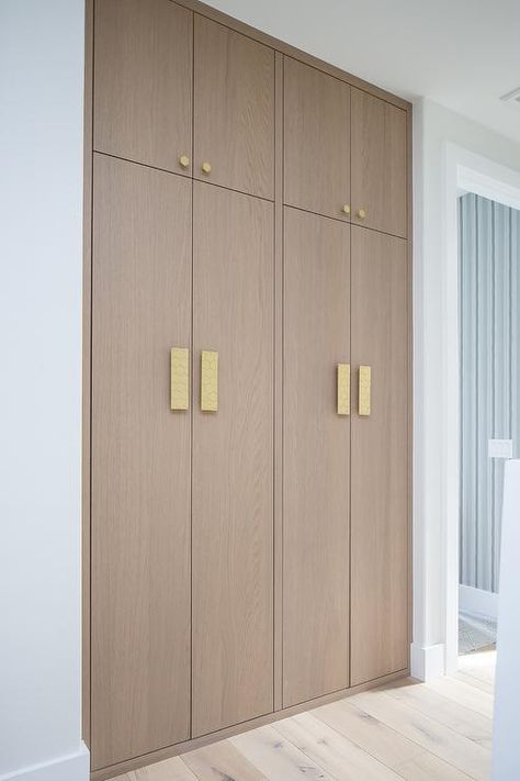 Brass hexagon hardware complements stacked floor-to-ceiling brown oak hallway cabinets. Hallway Storage Ideas, Oak Hallway, Hallway Cabinets, White Beveled Subway Tile, Hallway Storage Cabinet, Floor To Ceiling Cabinets, Hall Cabinet, Hallway Cabinet, Ceiling Storage