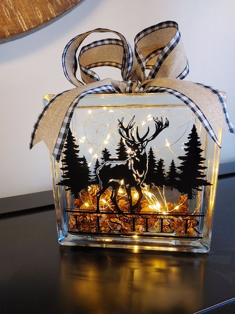 "Add some cozy and rustic charm to your home with this unique glass block light. This 7.5\" glass block contains a pair of battery powered string lights that create a warm and inviting glow. The front of the block is decorated with a deer and trees design that gives it a woodland feel. You can also personalize it with your family name for a custom touch. The block is finished off with a bow made of burlap ribbon with buffalo plaid edging. This glass block light is perfect for any room in your ho Glass Boxes With Lights, Ideas For Glass Blocks, Fall Glass Block Ideas, Glass Blocks Crafts, Wedding Glass Block Ideas, Glass Block Decorating Ideas, Glass Block Crafts Diy, Glass Box Ideas, Decorated Glass Blocks