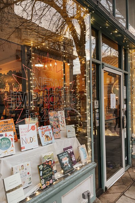 The cozy storefront of Curious Iguana. Blue trim, books in the window, and twinkling lights. Small Cozy Bookstore, Indie Bookstore Aesthetic, Small Bookstore Design, How To Open A Bookstore, Opening A Bookstore, Cozy Bookshop Aesthetic, Bookstore Lighting, Bookstore Layout, Cozy Bookstore Aesthetic