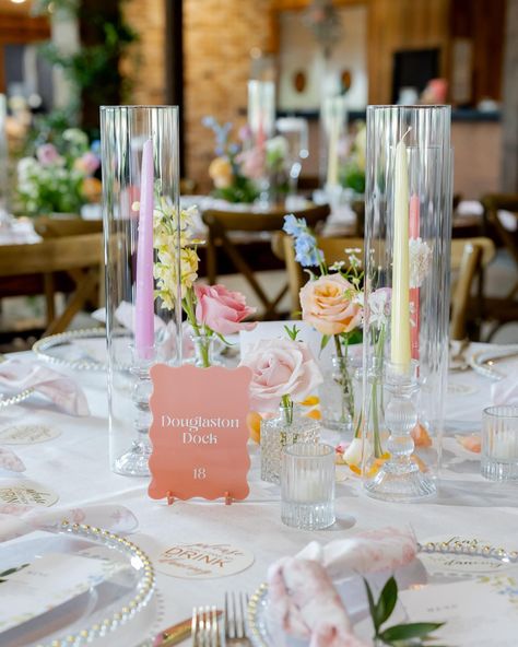 you kidding me 🥲 these pastel tapers added so much to this tablescape!! A sweet bud quartet paired with a trio of taper candles is one of our favorite ways to add a little something something to a guest table. here, we opted for mini centerpieces on some of our farm tables + invested in smilax vines to give life to the venue overall - which is something ALL your guests can enjoy, no matter which table they’re sat at. It’s all about creating an atmosphere! Planning @perfectlyplannedtx Venue... Table Setting Spring Wedding, Oval Table Wedding Decor, Candle Vase Centerpieces, Low Cost Wedding Table Decor, Pastel Table Centerpieces, Bud Flower Centerpieces, Wedding Reception Tables Decor, Round Table With Bud Vases, Bud Vases And Taper Candles Centerpiece