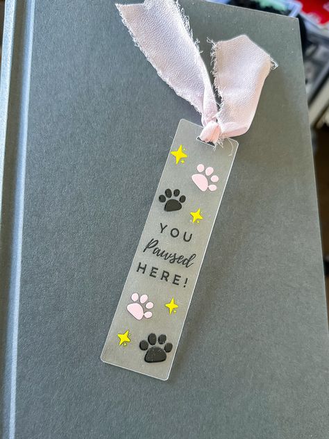 This "You Pawsed Here" acrylic bookmark is perfect to show off how much you love books and dogs!  Bookmark Details: ⚬ Dimensions: 4.7" x 1.3" ⚬ Lettering is made from UV permanent vinyl ⚬ Beautiful light pink organza ribbon for an added touch These make the perfect gift for a book lover, book club or yourself :) Thank you for visiting my Etsy shop! All of our items are handmade in the heart of South Dakota by me, a passionate dog momma :) Follow us on social media!  Facebook: https://bit.ly/3V16 Cricut Bookmarks, Dog Bookmarks, Bookmark Acrylic, Fun Bookmarks, Market Day Ideas, Acrylic Bookmarks, Homemade Bookmarks, Diy Dog Collar, Diy Bookmarks