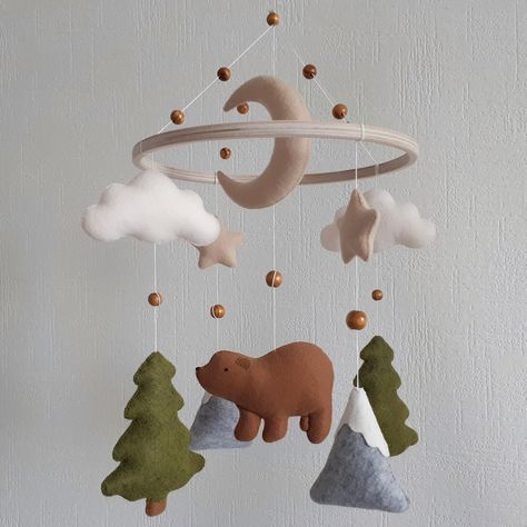 Woodland mobile nursery with bear is an ideal and original baby shower gift that will perfectly decorate the nursery baby girl or boy in the Scandinavian style.Your baby will love this cute bear and will not only enthusiastically consider them, also develop crib mobile teaches him to focus his eyesight. SIZE:the diameter of the ring ~ 22 cm (8,6 inch)full mobile length ~ 37 cm (14,5 inch) MATERIALS:Felt American, KoreanHypoallergenic holofiber fillerWooden ringbaseStrong cotton threadWooden bead Crib Mobile Ideas, Mountain Mobile Nursery, Winter Woodland Nursery, Forest Inspired Nursery, Brother Bear Nursery, Woodland Mobile Nursery, Boy Nursery Woodland Theme, Hunting Nursery Ideas, Boy Nursery Hunting Theme