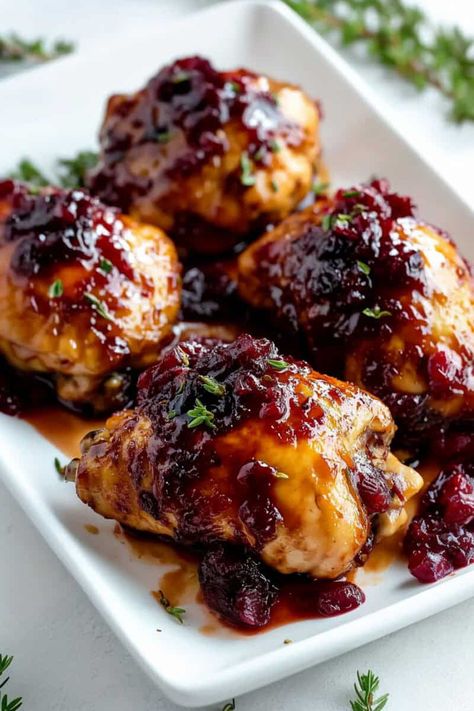 Succulent cranberry chicken thighs glazed with a sweet and tangy cranberry sauce, garnished with fresh thyme, served on a white platter. Dinner With Cranberries, Blueberry Balsamic Chicken, Raspberry Vinaigrette Chicken, Chicken And Cranberry Sauce Recipes, Christmas Chicken Thigh Recipes, Orange Cranberry Chicken, Cranberry Sauce Chicken, Christmas Chicken Thighs, Healthy Christmas Meal Ideas