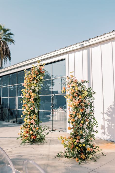 disconnected deconstructed wedding ceremony arch with lush orange yellow pink florals Ceremony Arch Flowers, Wedding Floral Arch, Garden Whimsical, Fall Ceremony, Floral Arch Wedding, Citrus Wedding, Wedding Ceremony Arch, Arch Flowers, Wedding Aisle Decorations