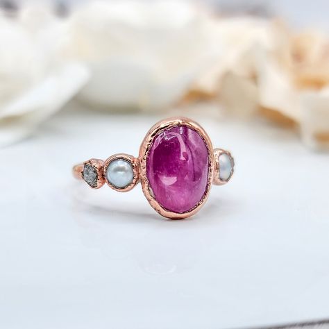 ♡ Ruby, Pearl, and Rough Diamond Ring Ruby: ❀ Happiness ❀ Laughter ❀ Courage Pearl: ❀ Emotional Balance ❀ Wisdom ❀ Intuition Diamond represents: ❀ Purity ❀ Harmony ❀ Love This ring features a stunning combination of vibrant ruby, lustrous pearl, and dazzling raw diamond set in warm rose gold. The deep red hue of the ruby contrasts beautifully with the soft glow of the pearl, while the raw diamond adds a touch of rugged elegance. The rose gold band ties the elements together, creating a u... Engagement Ring Pearl, Birthstone Jewelry Mothers, Raw Diamond Ring, Pearl Diamond Ring, Gold Ring Unique, Raw Diamond Rings, Rough Diamond Ring, Raw Crystal Ring, Pearl Engagement Ring