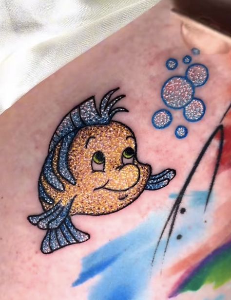 Flounder And Sebastian Tattoo, Disney Glitter Tattoo, Glitter Tattoos Real, Glitter Tattoo Ideas, Disney Sidekicks Tattoo, Music Symbol Tattoo, Little Mermaid Tattoo, Disney Sleeve, Mermaid Glitter