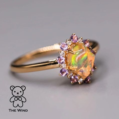 Hey everyone! Today, let me introduce the Mexican Fire Opal Amethyst Diamond Engagement Halo Ring in 18K Yellow Gold. Designed by our artist for someone truly special, this unique ring features a circle of amethyst embracing the Mexican Fire Opal. Ideal for engagements and anniversaries, its uniqueness ensures you won't find a match. Express your love uniquely! 💖 #EngagementRing #uniquelove #OpalJewelry #OpalLove #DiamondRing #FineJewelry #JewelryLove #Ring #JewelryMagic #DiamondHalo #LuxuryF... Fire Opal Wedding Ring, Opal Sapphire Ring, Gold Opal Rings, Rarest Gemstones, Opal And Sapphire Ring, Fire Opal Engagement Ring, Opal Promise Ring, Mexican Fire Opal Ring, Dream Rings