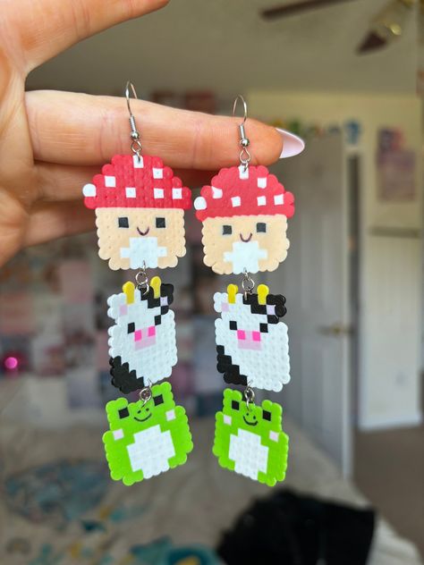 Squishmallow earrings made out of mini perler beads! Oogie Boogie Beaded Earrings, Earring Perler Beads, Mini Perler Bead Earrings, Perler Sanrio, Round Perler Bead Patterns, Perler Beads Earrings Ideas, Cartoon Perler Beads, Squishmallow Kandi, Squishmallow Perler Beads