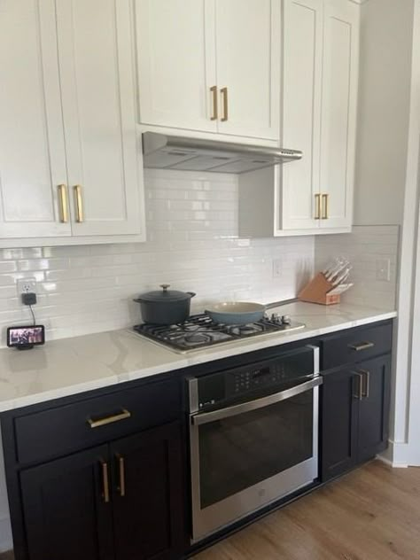 Black lower cabinets with white upper cabinets complimented by white subway tile backsplash with gold accents. Backsplash With Gold Accents, Black Lower Kitchen Cabinets, Black Lower Cabinets White Upper, Black Lower Cabinets, Navy Blue Kitchen Cabinets, White Upper Cabinets, Lower Cabinets, Upper Kitchen Cabinets, White Subway Tile Backsplash