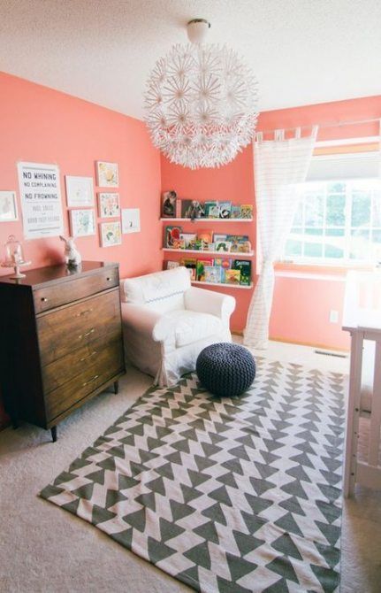 a cheerful grey and coral nursery with coral walls, a printed rug, a stained sideboard, a cool chandelier and whiet touches Coral Painted Walls, Baby Room Colors Girl, Baby Girl Neutral Nursery, Colorful Baby Room, Girl Neutral Nursery, Coral Nursery Decor, Disney Baby Rooms, Colorful Baby Nursery