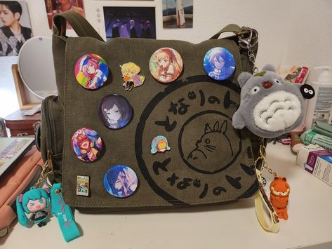 aesthetic messenger bag keychains pins cute School Messenger Bag Aesthetic, Messenger Bag Ideas, Messenger Bag Decoration, Messenger Bag Pins, Decorated Messenger Bag, Pins On Bag, Aesthetic Messenger Bag, Messenger Bag With Pins, Bag Pins Aesthetic