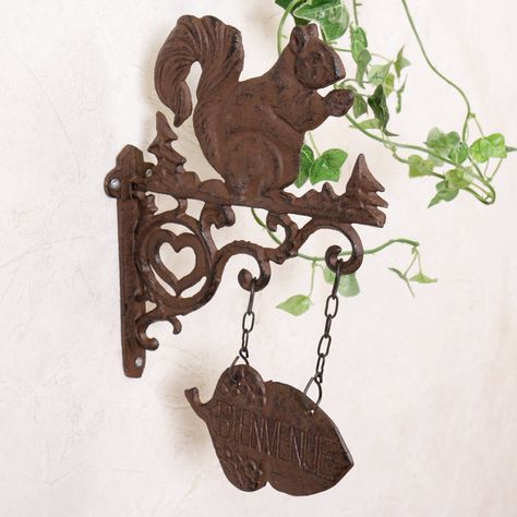 Decorative iron wall plaque perfect for adding vintage country style to the entrance. Making a lovely gift idea.Made from cast iron finished in an rustic antique brown this lovely country squirrel welcome sign is a great addition to the entrance of your home. Featuring a decorative hanging acorn welcome sign with the wording "Bienvenue" this French country style wall bracket makes a great garden or doorstop accessory.Cast ironH30 x L19cm Welcome Hanging Sign, Cast Iron Hanging, Welcome Sign Decor, Welcome Hanging, Squirrel Nutkin, Vintage Country Style, Squirrel Decor, Home Decor Brown, Squirrel Gift