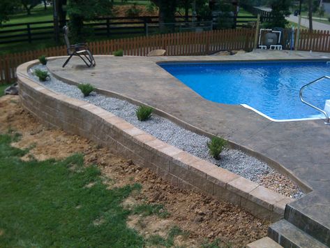 inground pool with retaining wall | An inground liner pool with a stamped concrete pool deck. In Ground Pool Sloped Yard, Inground Pool Ideas Sloped Yard, Retaining Wall Around Pool, Poolside Landscaping, Pool Retaining Wall, Pool Concrete, Deck Addition, Inground Pool Landscaping, Pool Pavers