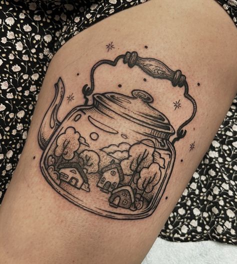 Thigh tattoo of a tea kettle with tiny houses and trees inside done in black line and dot style. Tea Kettle Tattoo, Kettle Tattoo, White Tea Kettle, Cottagecore Tattoo, Teapot Tattoo, Cottagecore Tea, Tea Tattoo, Teacup Tattoo, Casino Tattoo