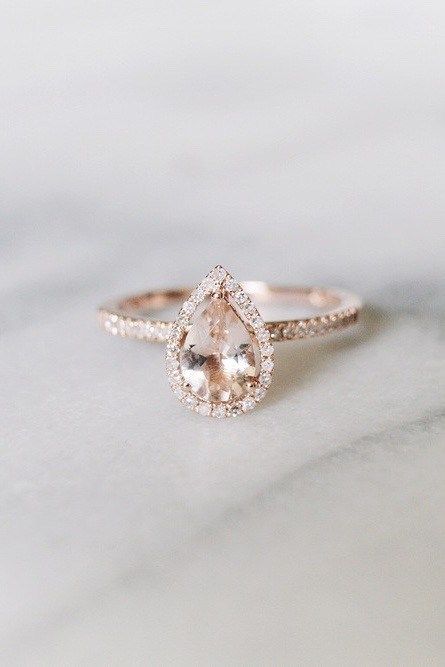 A Pear Shaped Diamond Engagement Ring With Halo Diamonds Sits On A Marble Table. Pear Shaped Diamond Engagement Rings, Top Engagement Rings, Marriage Ring, Stunning Engagement Ring, Stylish Rings, Dream Engagement Rings, Rose Gold Engagement, Halo Engagement Rings, Pear Shaped Diamond