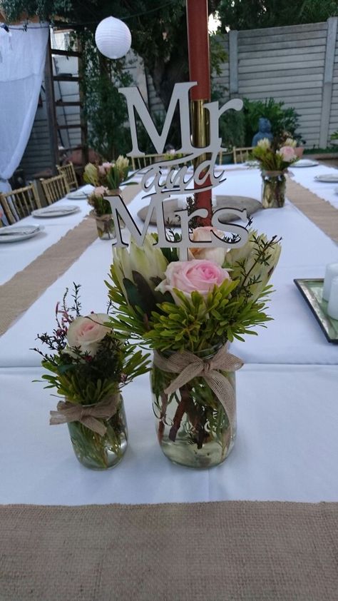 Backyard bbq flower arrangement: Proteas,  roses and fynbos in jam jars with hessian ribbon. Flowers With Ribbon, Jam Jar Flowers, Jar Flowers, Jam Jars, Bbq Party, Jam Jar, Backyard Bbq, Flower Arrangement, South African