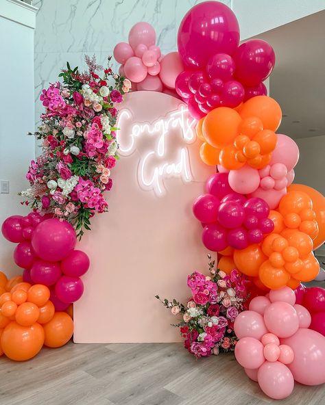 Celebrate your graduating princess with our stunning orange and pink balloon setup, complete with beautiful florals, a custom neon sign, and a chic backdrop! 🎈🌸✨ The perfect setting for an unforgettable graduation day. ✨🥳 Pink And Orange Balloon Backdrop, Pink Orange Backdrop, Balloon Floral Backdrop, Graduation Party Pink And Orange, Floral Balloon Backdrop, Pink And Orange Backdrop, Pink And Orange Balloons, Orange And Pink Grad Party, Pink And Orange Decorations