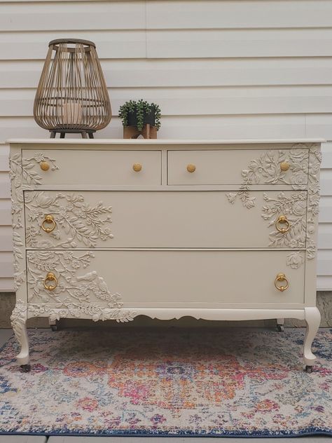 This gorgeous 100 year old dresser has been brought back to life! We called her 'Lady', and she will add a beautiful floral accent to any home. Adorned with hand-placed resin flowers and painted in Cathedral Taupe from Fusion Mineral Paint, Lady is a feminine yet versatile addition to your decor. Refinished gold hardware opens the deep, roomy, dovetailed drawers. The polyacrylic finish adds durability to this solid wood piece, and the casters make adding her to your space a breeze! Dresser Stickers Drawers, Iod Molds Dresser, Dresser With Flowers In Drawers, Furniture With Flower Molds, Resin Flowers On Furniture, Floral Dresser Diy, Wood Applique On Furniture, Cottage Core Dresser, Dresser With Flowers