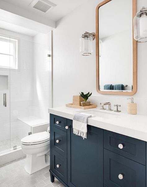 Placed on gray subway floor tiles, a dark blue bath vanity is accented with a white quartz countertop and backsplash fixed under a curved wooden vanity mirror lit by nickel and glass sconces. Navy Vanity, Charming Bathroom, Brooke Wagner, Blue Vanity, Wooden Bath, Wooden Vanity, Blue Bath, Transitional Bathroom, White Quartz Countertop