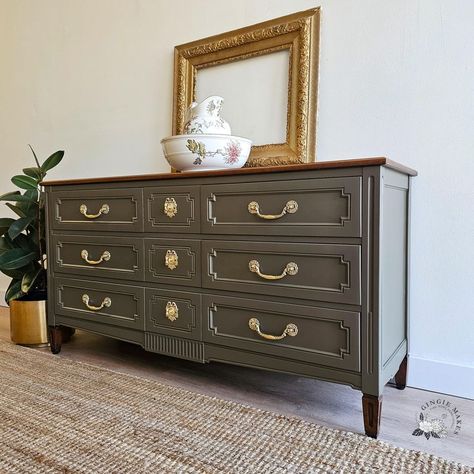 this Cherry triple dresser has had a beautiful update, modernizing the piece while keeping its Provincial charm. The top was brought down to the raw cherry and then stained a rich brown. The body was painted in high quality mineral paint in a stunning neutral with green and brown undertones. . . #solidwood #vintage #modern #restoredfurniture #c #credenza #dyi #shoplocal #DIYFurniture #furniturerefurbishing #furniturerefurbished #furniturerefurbish #furniturerefinishing #furniturerefinish #fu... Olive And Wood Dresser, Dark Wood Dresser With Gold Hardware, Heywood Wakefield Dresser, Triple Dresser, Antique Bow Front Dresser, Datk Brown Dresser, Mineral Paint, Weathered Wood, Furniture Restoration