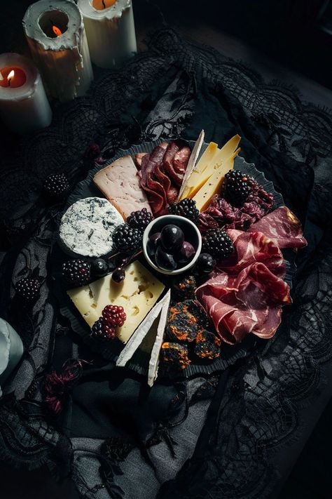 Dark-themed charcuterie board with assorted cheeses, cured meats, blackberries, and olives, placed on a vintage black lace cloth with candlelight for dramatic effect. Food Bar Aesthetic, Halloween Fine Dining, Spooky Food Board, Luxury Party Food, Charcuterie Night, Halloween Catering Ideas, Cute Halloween Charcuterie Board, Samhain Party Ideas, Charcuterie Board With Pomegranate